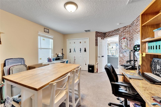 carpeted office space featuring brick wall and a textured ceiling