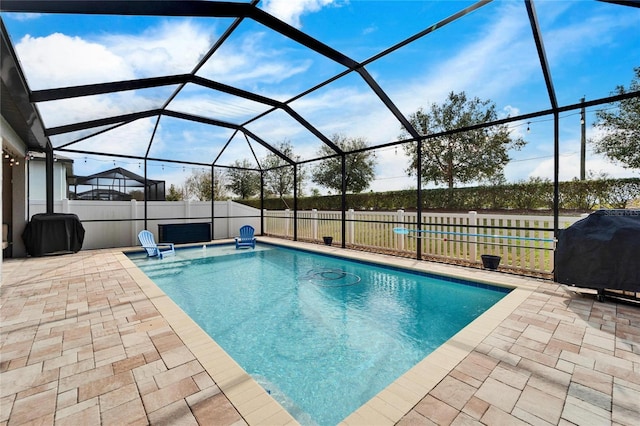 view of pool with a lanai, grilling area, and a patio