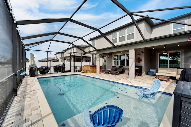 view of pool with glass enclosure, ceiling fan, a patio area, and an outdoor hangout area