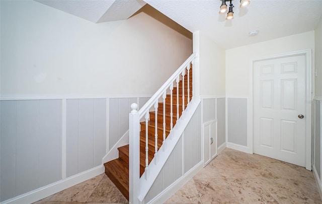 staircase featuring a textured ceiling and a notable chandelier