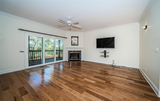 unfurnished living room with ornamental molding, a textured ceiling, ceiling fan, hardwood / wood-style flooring, and a premium fireplace