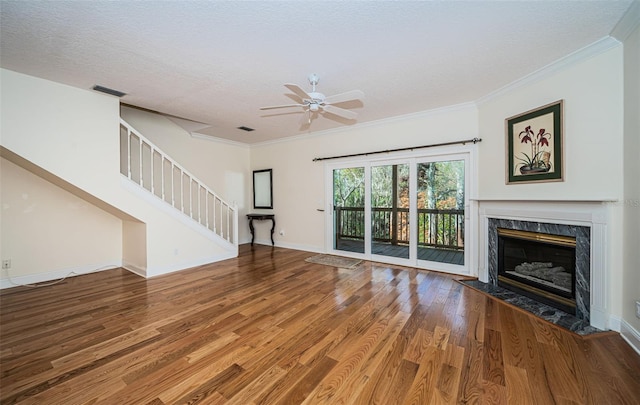 unfurnished living room featuring ceiling fan, a high end fireplace, crown molding, a textured ceiling, and hardwood / wood-style flooring