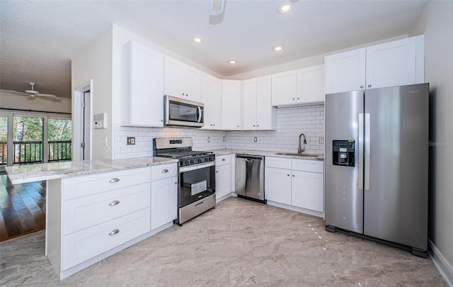 kitchen with kitchen peninsula, white cabinetry, sink, and stainless steel appliances