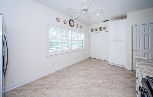 unfurnished bedroom with ceiling fan, a textured ceiling, stainless steel refrigerator, and a closet