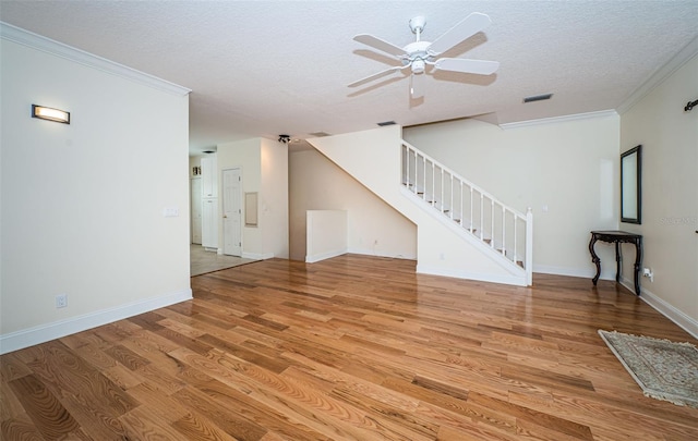 unfurnished living room featuring ceiling fan, light wood-type flooring, a textured ceiling, and ornamental molding