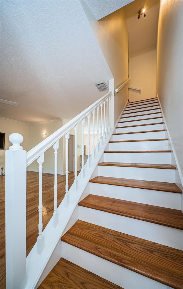 staircase with a textured ceiling and hardwood / wood-style flooring