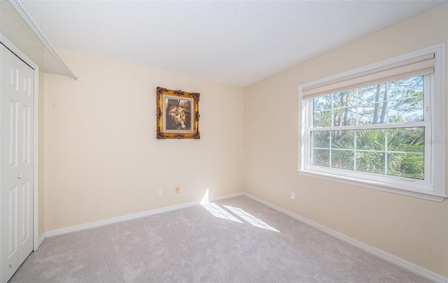 unfurnished bedroom with a closet and light colored carpet