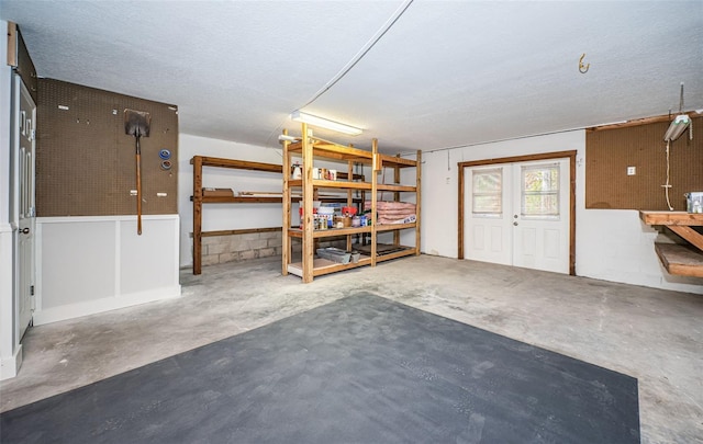 basement featuring a workshop area, a textured ceiling, and french doors