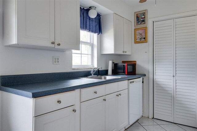 4215 E Bay Dr Unit 104, Clearwater, FL 33764 - kitchen with dark countertops, white dishwasher, white cabinets, black microwave, and light tile patterned flooring