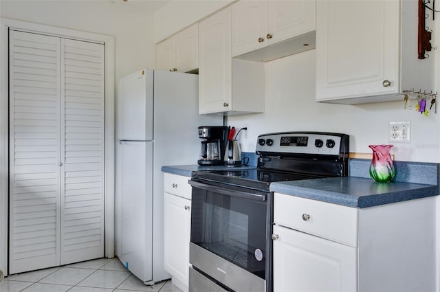 kitchen with stainless steel electric stove, light tile patterned flooring, and white cabinetry