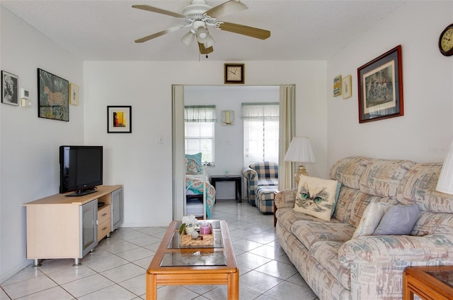 living room featuring ceiling fan, light tile patterned floors, and a textured ceiling