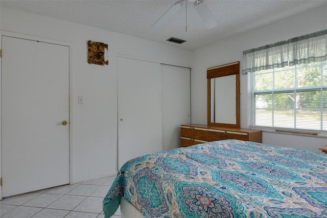 tiled bedroom with ceiling fan and a textured ceiling