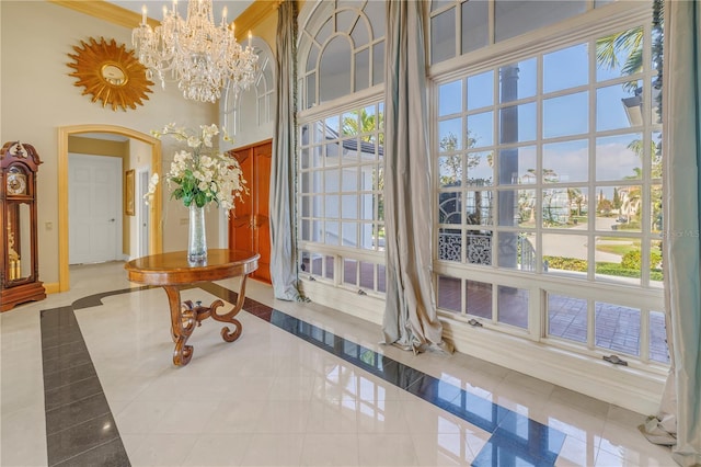 doorway to outside featuring plenty of natural light, light tile patterned flooring, a chandelier, and a high ceiling