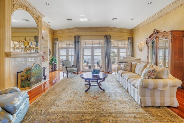 living room with hardwood / wood-style floors, built in features, ornamental molding, and french doors