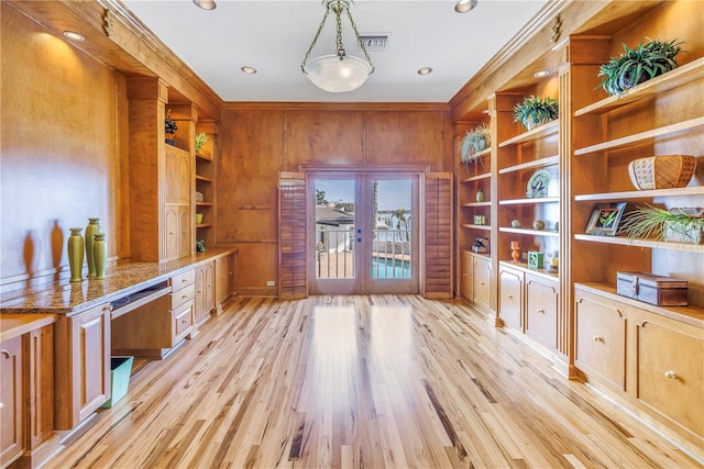 office featuring french doors, light wood-type flooring, crown molding, built in desk, and wood walls