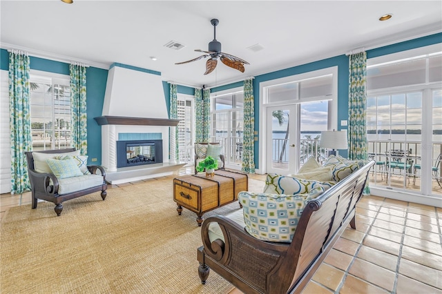 tiled living room featuring a tile fireplace, ceiling fan, and ornamental molding