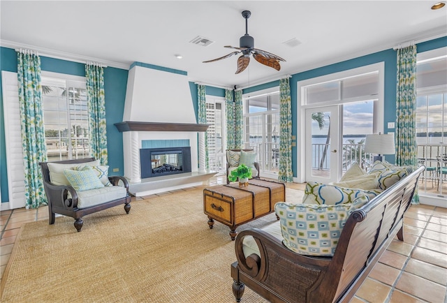 interior space featuring ceiling fan, light tile patterned flooring, ornamental molding, and a fireplace