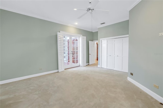 unfurnished bedroom with french doors, ceiling fan, ornamental molding, light colored carpet, and a closet