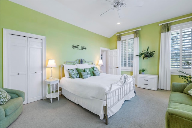 bedroom featuring ceiling fan, a closet, light carpet, and lofted ceiling