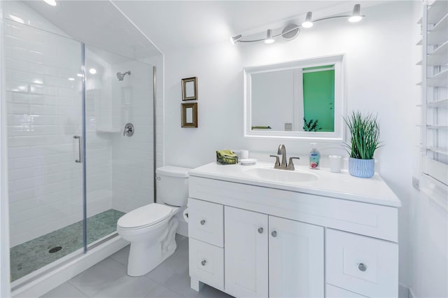 bathroom featuring toilet, vanity, tile patterned floors, and a shower with door