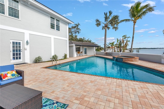 view of swimming pool with a patio area, a water view, and an in ground hot tub