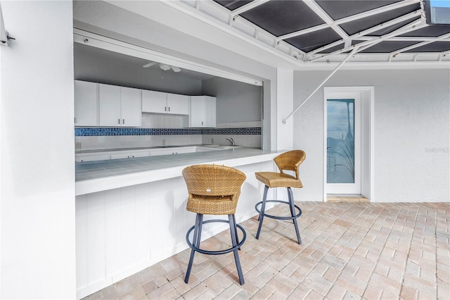 kitchen featuring white cabinets, decorative backsplash, a breakfast bar, and sink