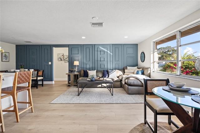 living room with a textured ceiling and light hardwood / wood-style flooring