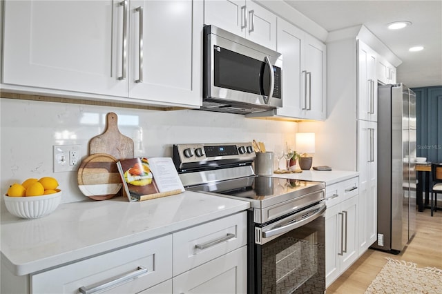 kitchen with light stone counters, white cabinetry, appliances with stainless steel finishes, and light hardwood / wood-style flooring