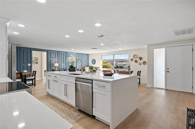 kitchen with white cabinetry, dishwasher, sink, an island with sink, and light wood-type flooring