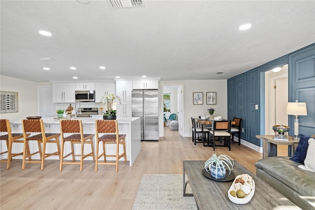 living room featuring a textured ceiling, light wood-type flooring, and sink