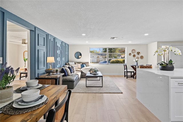 living room with a textured ceiling and light wood-type flooring