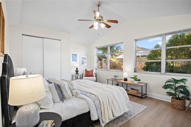 bedroom with a closet, ceiling fan, hardwood / wood-style floors, and vaulted ceiling