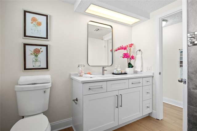 bathroom featuring vanity, toilet, wood-type flooring, and a textured ceiling