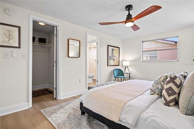 bedroom featuring a walk in closet, ceiling fan, light wood-type flooring, a textured ceiling, and a closet