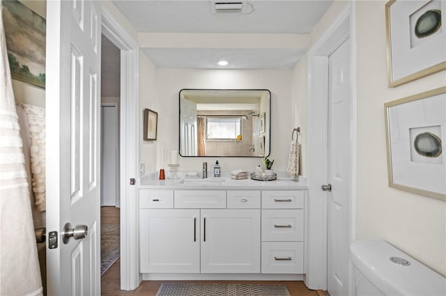 bathroom featuring hardwood / wood-style floors, vanity, a textured ceiling, and toilet