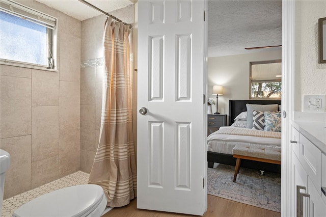 bathroom featuring hardwood / wood-style floors, a textured ceiling, a wealth of natural light, and curtained shower