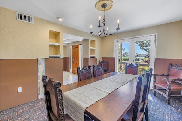 dining area featuring built in shelves, french doors, and an inviting chandelier