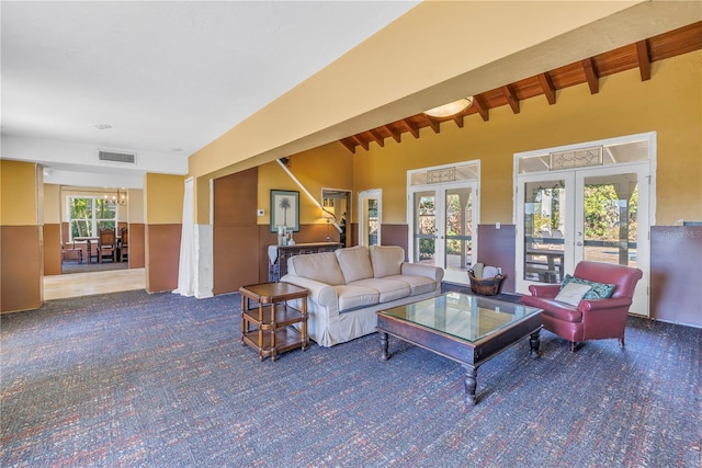 carpeted living room with vaulted ceiling with beams and french doors