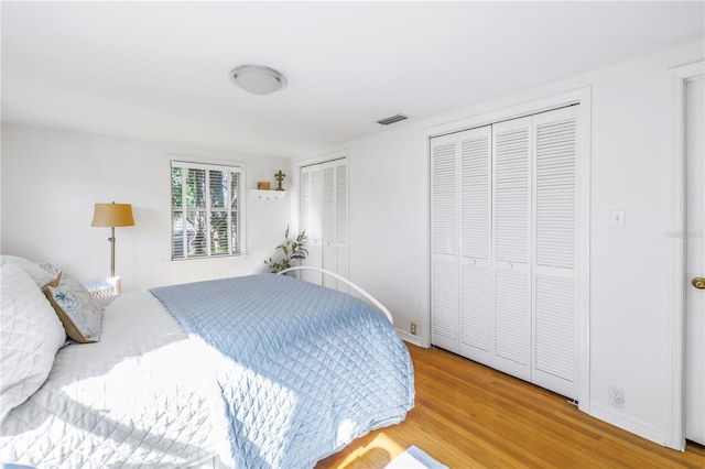 bedroom with hardwood / wood-style floors and two closets