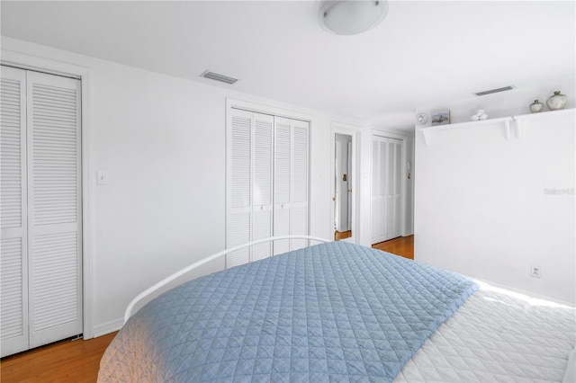 bedroom featuring light hardwood / wood-style flooring and multiple closets