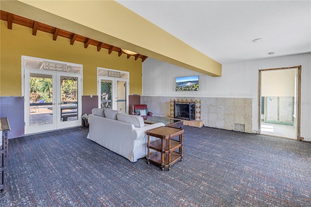 living room featuring french doors, a tiled fireplace, and beam ceiling