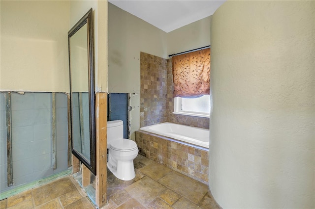 bathroom with a relaxing tiled tub and toilet