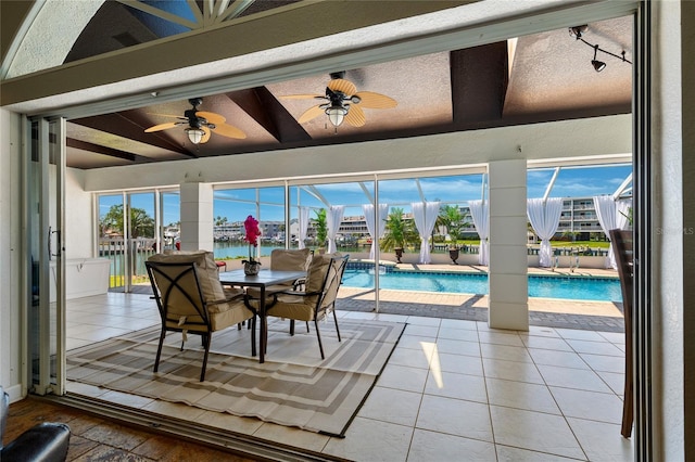 dining room featuring beam ceiling, light tile patterned flooring, a ceiling fan, and a sunroom