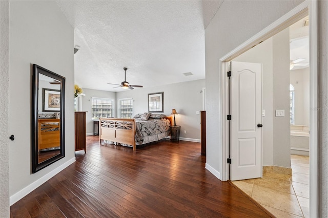 bedroom featuring baseboards, wood finished floors, and a textured ceiling