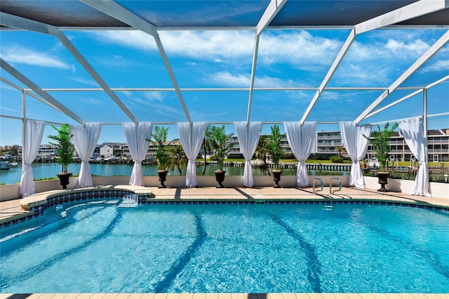 outdoor pool with glass enclosure, a patio, and a water view
