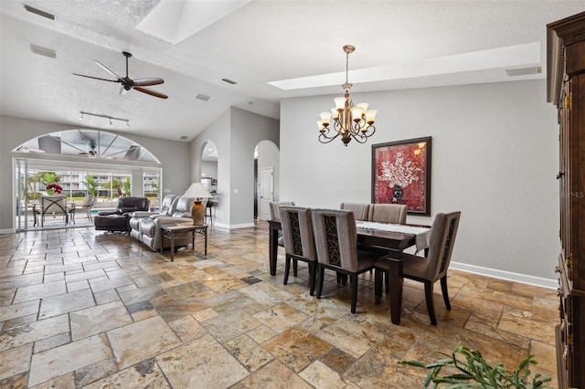 dining area featuring arched walkways, a textured ceiling, stone tile floors, and baseboards