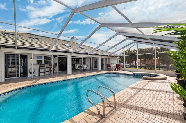 pool with glass enclosure, a patio, and an in ground hot tub