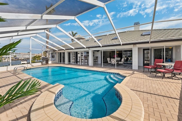 pool with a patio area, glass enclosure, and area for grilling