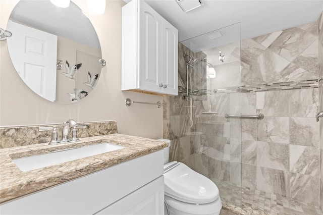 bathroom with a tile shower, vanity, and toilet