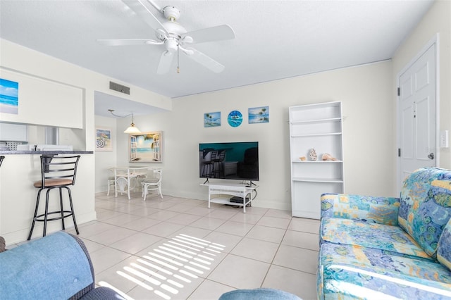 living room with a textured ceiling, ceiling fan, and light tile patterned flooring